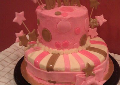 A pink birthday cake decorated with star-shaped toppings on sticks, with the word "DIVA" written on it
