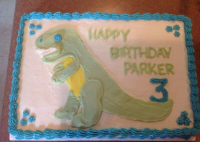 A unique cake decoration for a 3-year-old child named Parker, featuring a dinosaur theme. The cake is designed with dinosaur decorations, perfect for a young child's birthday celebration